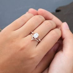 a woman's hand holding an engagement ring with two diamonds on top of it