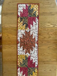 a wooden table with a red and yellow quilt on it