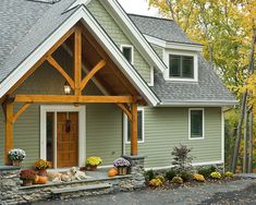 a green house with two dogs on the front porch and one dog laying in the driveway