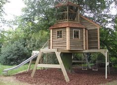 a tree house with a slide in the yard