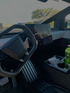 the interior of a vehicle with an electronic device and drinks on the table in front of it