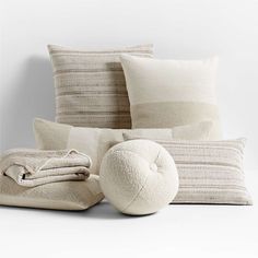 pillows and blankets are stacked on top of each other in front of a white wall