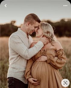 a pregnant couple cuddles in an open field