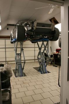 a car being worked on in a garage with two lifters attached to the ceiling