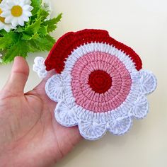 a hand is holding a crocheted flower brooch