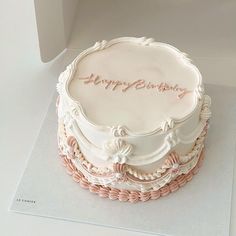 a birthday cake with white frosting and pink decorations on the top is sitting in a box