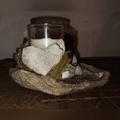 a candle sitting on top of a rock next to a bowl filled with rocks and other items