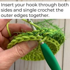 someone is crocheting the ends of their green yarn to make a hole in the fabric