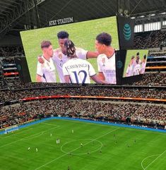 a soccer stadium filled with lots of people watching a game on large screen tvs