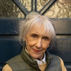 an older woman wearing a vest and smiling