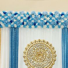 a blue and white decorated stage with flowers on the top, along with gold accents