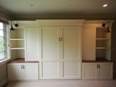 an empty room with built - in cabinets and shelves on either side of the window