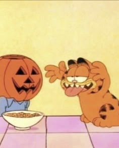 garfield the cat eating cereal from a bowl with jack o lantern on it's face