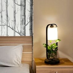 a lamp that is on top of a night stand next to a bed with pillows