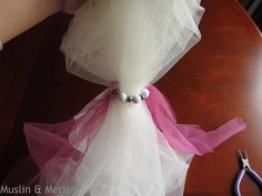 a dress made out of tulle and beads on a table with pliers next to it