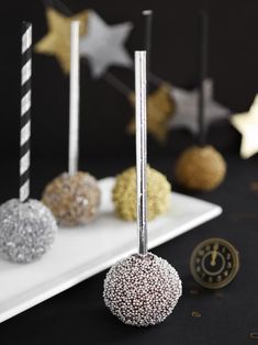 some cake pops are on a white plate with black and gold decorations in the background