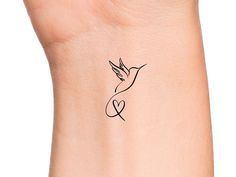 a small tattoo on the wrist of a woman's left arm with a bird flying above it