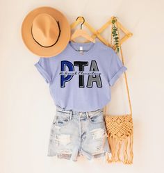 a t - shirt that says dta sits next to shorts and a straw hat