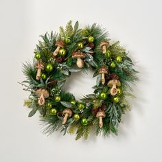 a christmas wreath hanging on the wall with ornaments and greenery around it's edges