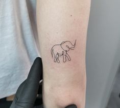 a small elephant tattoo on the left inner arm and shoulder, with one line drawn across it