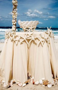 the table is set up on the beach for an outdoor wedding ceremony with seashells and starfish