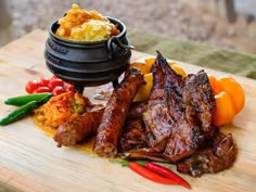 some meat and vegetables on a cutting board with a caulder full of food