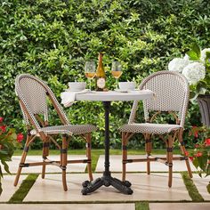 two chairs and a table in front of some bushes