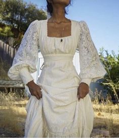 a woman in a white dress is standing outside