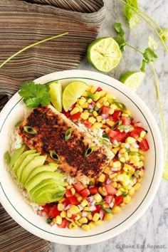 a white bowl filled with fish, corn and avocado on top of rice