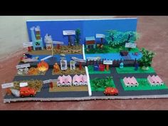 a paper model of a small town with cars and trucks on the road in front of it