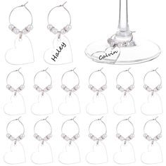 wine glass charms with names on them and hearts hanging from the top, all in clear plastic