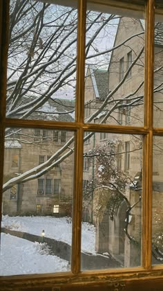 an open window looking out onto a snowy yard with trees and buildings in the background