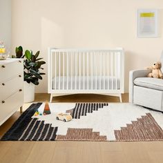 a baby's room with a white crib, rocking chair and toy bear