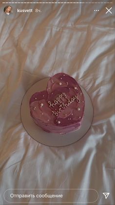 a heart shaped cake sitting on top of a white tablecloth covered sheeted bed