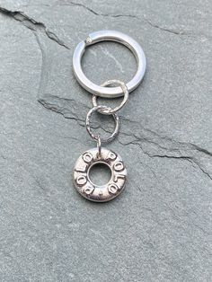 a metal keychain with the word love on it sitting on top of a rock