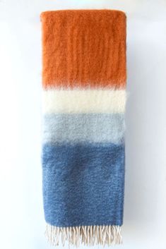 an orange, blue and white blanket hanging on a wall