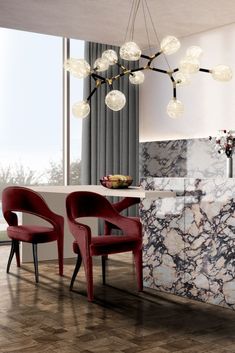 two red chairs sitting in front of a marble counter top next to a dining room table