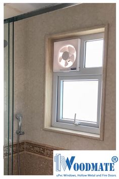 a bathroom with a window, toilet and shower head mounted to the side of the wall