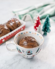 a cup filled with chocolate frosting sitting on top of a counter next to christmas decorations