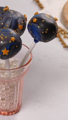 two chocolate lollipops with gold stars on them sitting in a glass cup