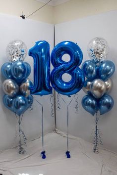 blue and silver balloons with the number eighteen displayed in front of a white wall,