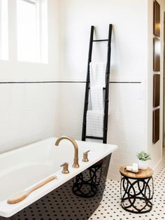 a white bath tub sitting next to a black and white tiled floor