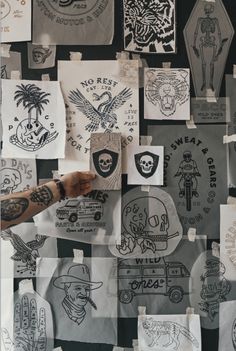 a person is holding up some paper with tattoos on it and there are many different designs all over the place