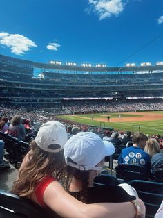 two people sitting in the bleachers watching a baseball game on a sunny day