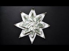 an origami snowflake made out of dollar bills on a black background