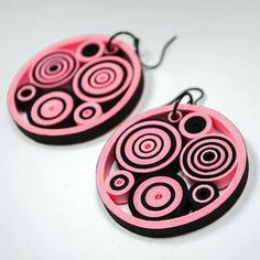 two pink and black earrings with circles on them