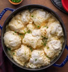 cauliflower in a blue pot on a wooden table next to other dishes and spoons