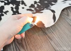 a person lighting a lighter on top of a cow print rug with wood flooring