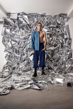 a man standing in front of a pile of shiny aluminum foil covering the walls and floor