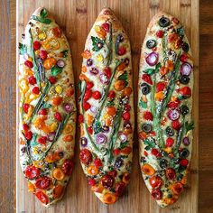 three different types of bread on a cutting board with tomatoes, onions, and other veggies